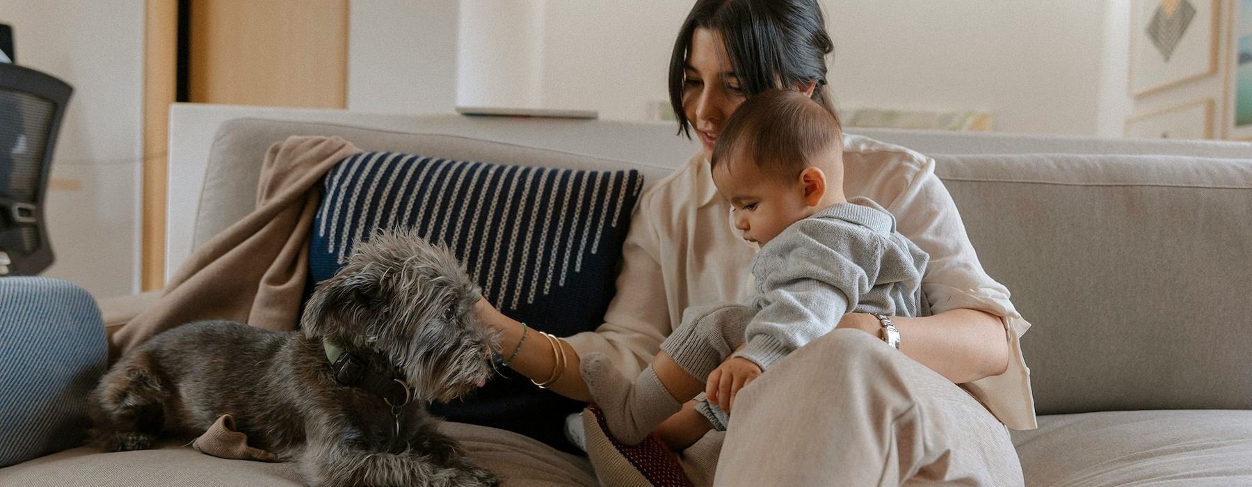 A woman and a baby on a couch with a dog.